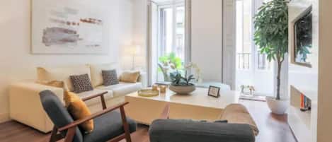 En moderne stue med sofa, stole, sofabord og en potteplante.