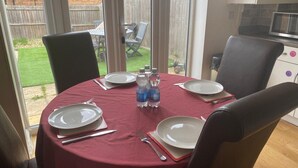 Een eettafel gedekt voor vier personen, met borden, bestek en waterflessen.