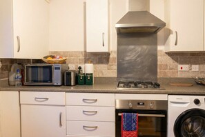 A kitchen with a microwave, toaster, kettle, and a washing machine.