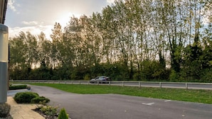 Een weg met een auto, een vangrail en bomen op de achtergrond.