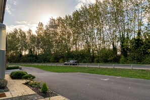 A road with a car, a guardrail, and trees in the background.