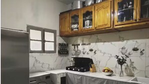 Una cocina con suelo de mármol, armarios de madera, refrigerador de acero inoxidable, lavadora y salpicadero de azulejos.
