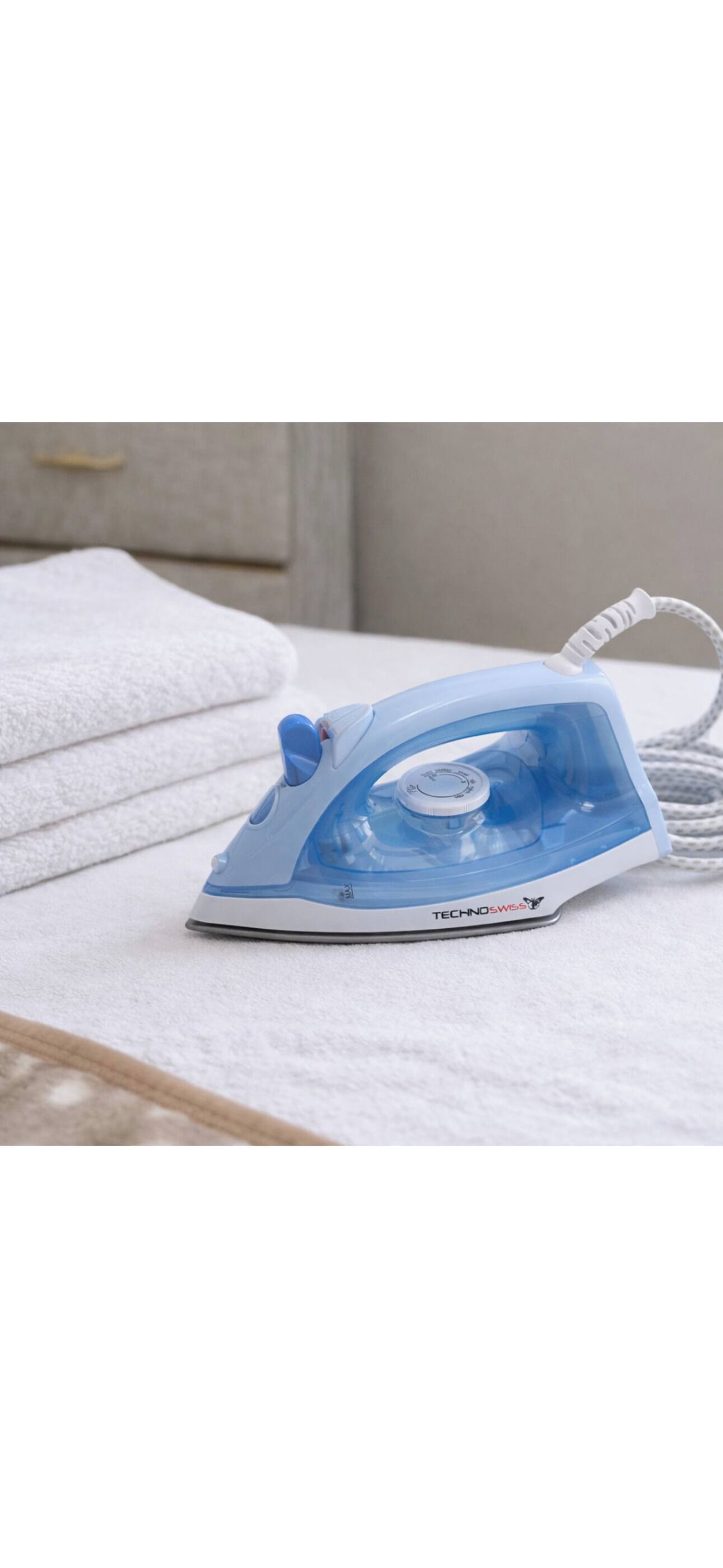 A blue iron on a white surface with a towel in the background.