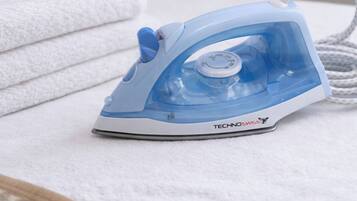 A blue iron on a white surface with a towel in the background.