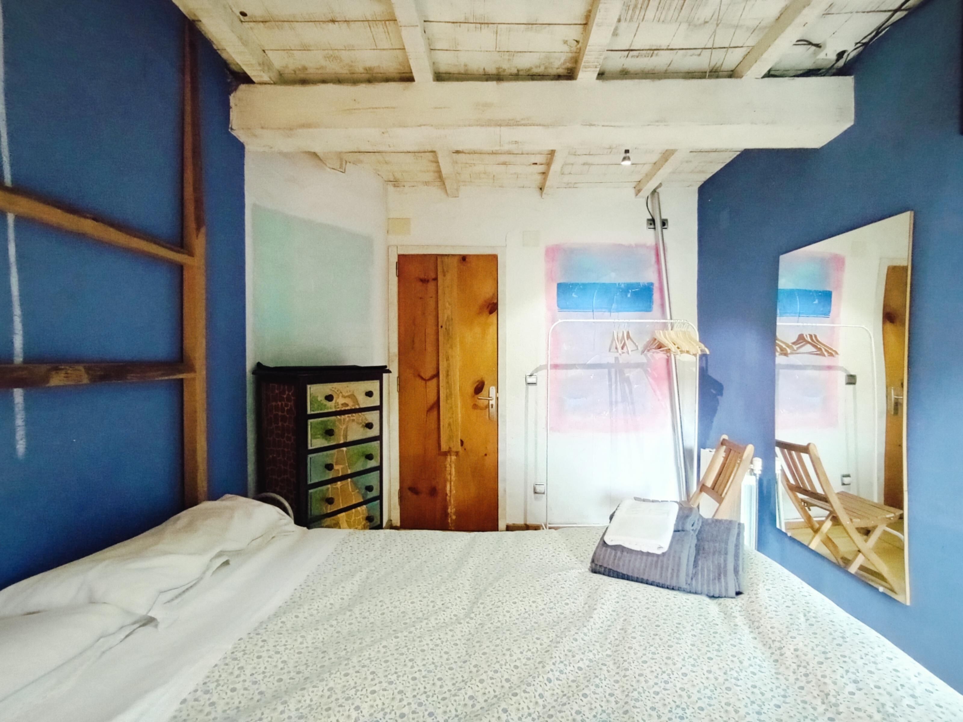 Een slaapkamer met een bed, een kaptafel, een spiegel en een deur naar een andere kamer.