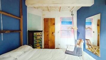 Een slaapkamer met een bed, een kaptafel, een spiegel en een deur naar een andere kamer.