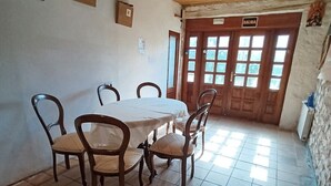 A dining area with a round table and chairs, a tiled floor, wooden ceiling beams, and a door labeled 'SALIDA'. - Double Room Azul - Private Bathroom - Cartes (Cartes)