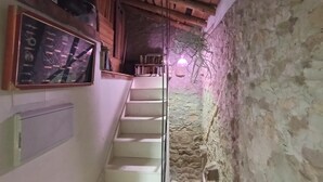 A narrow staircase leading to a wooden ceiling, with a stone wall on one side and a shelf with various items on the other. - Double Room Azul - Private Bathroom - Cartes (Cartes)
