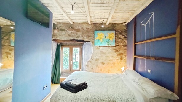 A bedroom with a bed, a stone wall, a painting, and a window with curtains. - Double Room Azul - Private Bathroom - Cartes (Cartes)