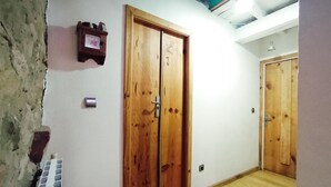 A room with wooden double doors, a small shelf with items, a radiator, and a wooden floor. - Double Room Azul - Private Bathroom - Cartes (Cartes)