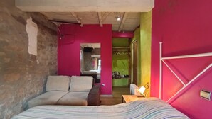Una stanza con un letto, un divano, un tavolo in legno e uno specchio.