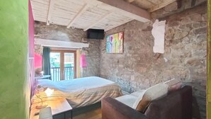 Una camera da letto con un letto, un divano, un tavolo e un quadro appeso al muro.