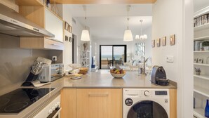 A modern kitchen with a Bosch range hood, an LG washing machine, and a bowl of fruit on the counter. - Apartment 'Sa Calma I - 1A' with Sea View, Wi-Fi and Air Conditioning (Begur)