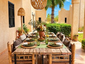 Taula de menjador preparada per a dinar, amb vista a un jardí i palmeres.