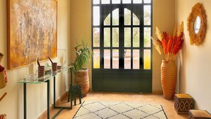 Passadís amb taula de vidre, planta en test, mirall decoratiu i una porta amb vista.