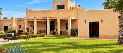 A building with a courtyard, outdoor seating, and palm trees.