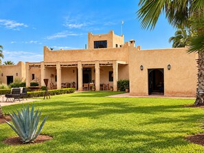 A building with a courtyard, outdoor seating, and palm trees.