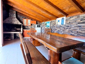 Una cucina rustica con camino in pietra, travi a cassetto in legno e un lungo tavolo di legno.
