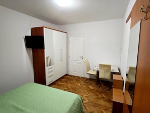 Una camera da letto con un letto, un armadio, una scrivania e una sedia.