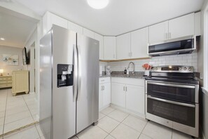 Een moderne keuken met roestvrijstalen apparatuur, witte kastjes en een inbouwmagnetron.