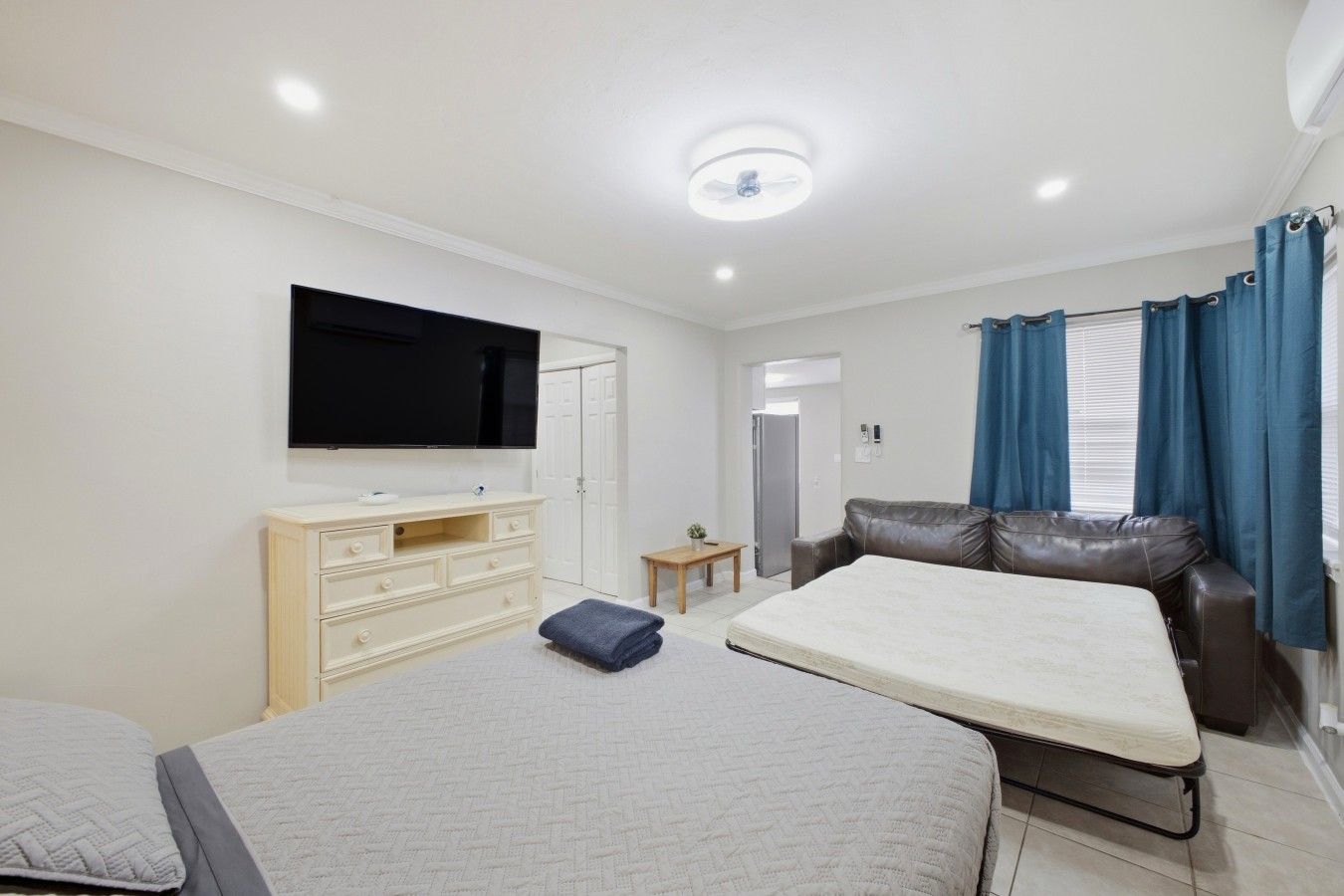 Een moderne slaapkamer met een flatscreen televisie, een bank, een bed en een klein tafeltje.