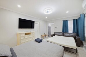 Een moderne slaapkamer met een flatscreen televisie, een bank, een bed en een klein tafeltje.