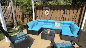 Une terrasse avec un canapé d’angle, deux fauteuils et une table basse.