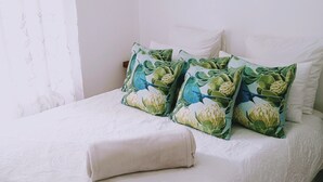 A bedroom with a bed, pillows, a blanket, and a curtain. - Room-charming Guest Room With Private Fa (Gqeberha)