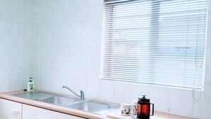 A kitchen with a sink, cabinets, a window with blinds, and a coffee maker on the counter. - Room-charming Guest Room With Private Fa (Gqeberha)