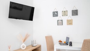 A modern room with a flat-screen TV, a wooden desk, two chairs, a laptop, a coffee cup, and motivational wall art. - Acqua Shanti Apartment (Piombino)