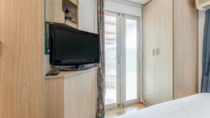 Ein Schlafzimmer mit einem Bett, einem Fernseher auf einem Schrank, einem Kleiderschrank und einer Schiebetür aus Glas.