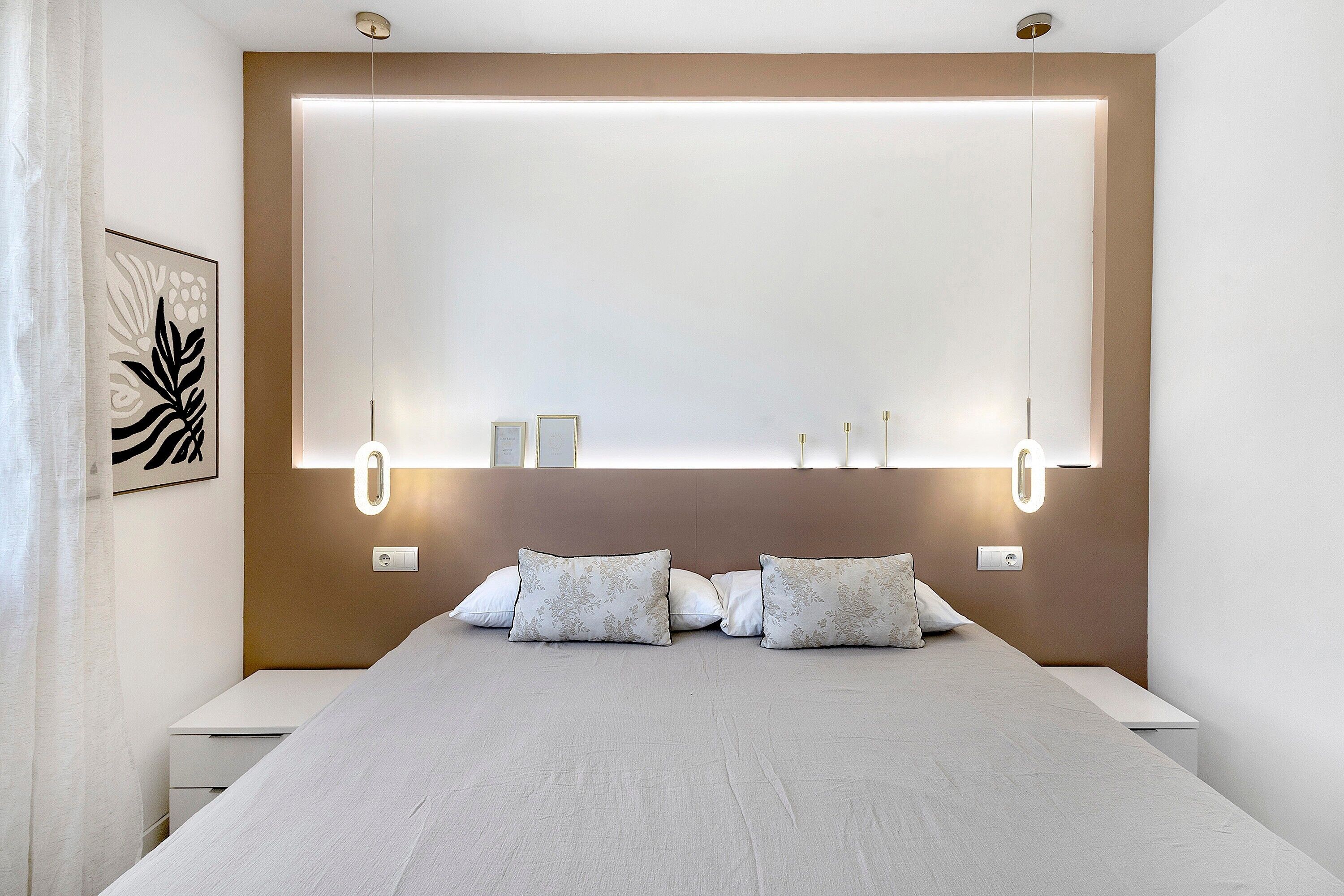 A modern bedroom with a large bed, bedside tables, and wall-mounted lighting.