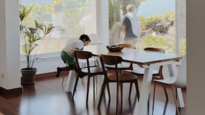 Ein Essbereich mit großem Fenster, Holzsesseln und einem Tisch.