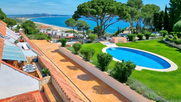 En boligejendom med swimmingpool, terrasse med udendørs møbler, havudsigt og et stort træ.
