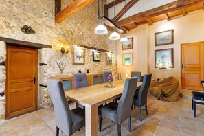A stone-walled dining area with a wooden table, chairs, and pendant lights. - Holiday Home 'Domaine Agenas' with Lake View, Private Pool and Wi-Fi (Monflanquin)