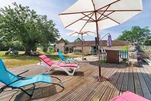 A wooden deck with lounge chairs and a large umbrella. - Holiday Home 'Domaine Agenas' with Lake View, Private Pool and Wi-Fi (Monflanquin)
