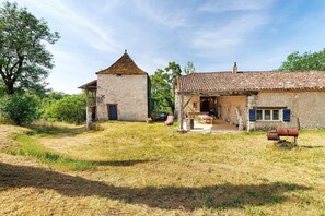 A rustic stone building with a tiled roof, a small tower, and a barrel in the yard. - Holiday Home 'Domaine Agenas' with Lake View, Private Pool and Wi-Fi (Monflanquin)