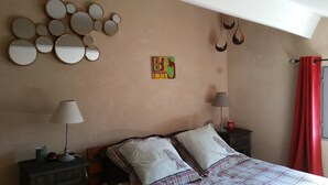 Een slaapkamer met een bed, twee nachtkastjes, een lamp, een spiegel en een wanddecoratie.