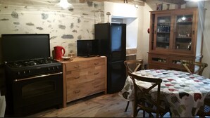 Een kleine keuken met een fornuis, koelkast en houten keukenkastjes.