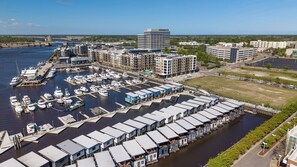 A marina with boats docked, a large building with a flat roof, and a parking area. - Modern 3BR Waterfront Houseboat | Walk to Wilmington Riverwalk and Dining (Wilmington)
