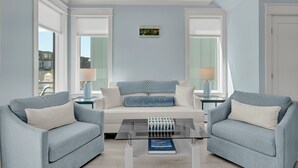 Una sala de estar moderna con un sofá, dos sillones, una mesa de centro y un cuadro en la pared.