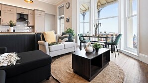 Eine moderne Küche mit Pendelleuchten, ein Essbereich mit Tisch und Stühlen sowie ein Ausblick durch große Fenster.