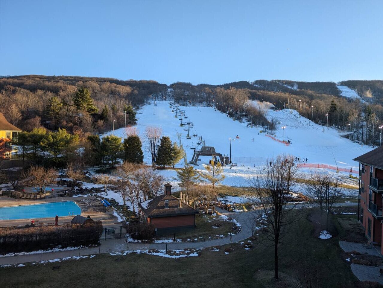 Een skigebied met een skilift, een zwembad en gebouwen.
