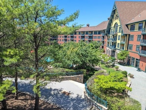 A multi-story hotel with balconies, a courtyard, and surrounding trees. - Amazing 1st floor Ski in/out Unit @ Creek (Vernon Township)