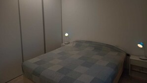 Makuuhuone, jossa on sänky, vaatekaappi, kaksi yöpöytävalaisinta ja yöpöytä.