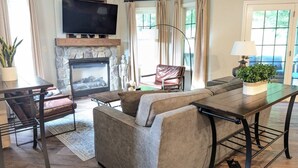 A living room with a fireplace, a television, a sofa, a dining table, and a lamp. - Spacious 3 bed 2 bath Sanctuary (Vernon Township)