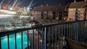 A nighttime view of a hotel with a swimming pool, multiple buildings, and a well-lit parking area. - 2 Bed Top Flr Prem Penthouse Suite (Vernon Township)