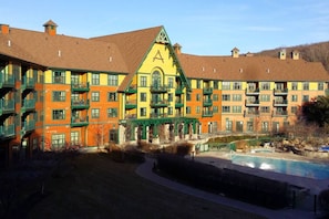 A multi-story hotel with a distinctive yellow and green facade, a central atrium, and a swimming pool.