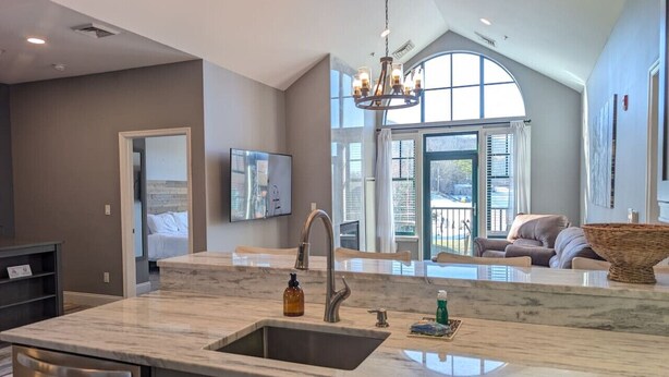 A modern kitchen with a large island, a built-in oven, and a large window with a view. - 2 Bed Top Flr Prem Penthouse Suite (Vernon Township)