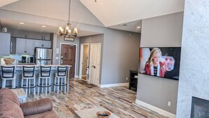 A modern kitchen with a bar area, a living room with a fireplace, and a TV mounted on the wall. - 2 Bed Top Flr Prem Penthouse Suite (Vernon Township)